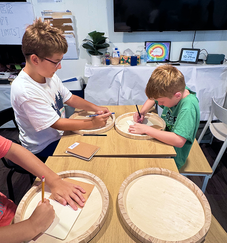 two students drawing on wood